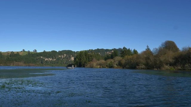 Fisherman fly fishing for trout from a drifting boat in Lake Whakamaru, New Zealand