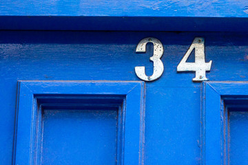 Silver house number thirty four with the 34 at the top on the door frame