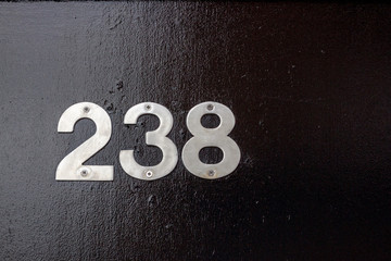 House number 238 with the two hundred thirty eight in silver numbers on a black door