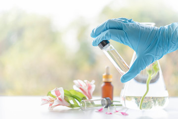 Close up bottle of essential oils with scientist holding dropper. Lab research for scent extract for the new skincare product.