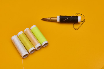 coils of thread with needles on yellow background