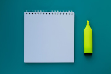 Blank notepad and yellow marker on a green table. Business concept. Education concept. Workspace. Open notepad on a green background. Copyspace.