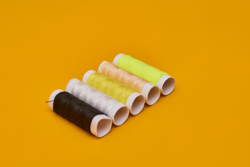 Fototapeta na wymiar coils of thread with needles on yellow background