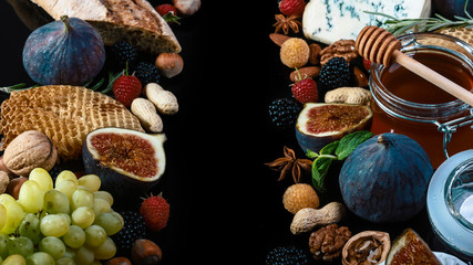 Cheese plate served with grapes, honey , figs, crackers and nuts on a black background. Food Frame. Top view. Copy space