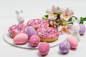 Easter bunnies and eggs on the table with donuts