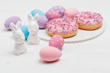 Easter bunnies and eggs on the table with donuts