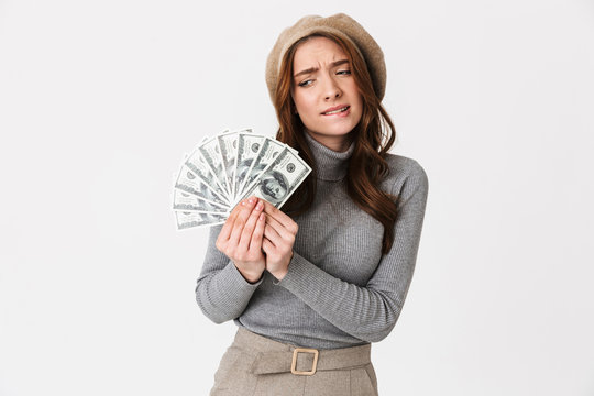 Confused beautiful woman holding money isolated over white wall background.