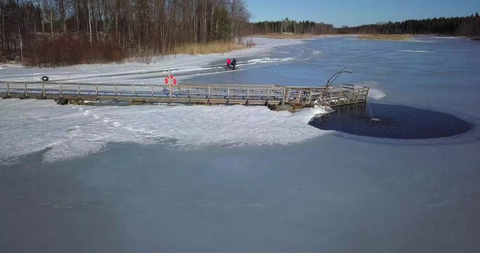Aerial, winter, ongoing aeration project to oxygenate lake, two women with stroller and kicksled enjoying sunny day on the ice