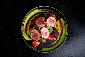 Delicious portion of healthy grilled lean medium rare beef steak cut through and served on a dark board garnished with vegatables