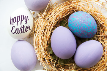 Multi-colored Easter eggs in nest on wooden background, selective focus image. Happy Easter card
