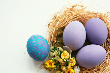 Multi-colored Easter eggs in nest on wooden background, selective focus image. Happy Easter card