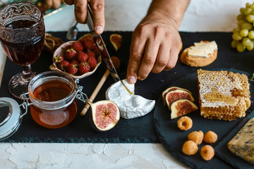 Camembert cheese with figs and nuts in hands in the kitchen. on wooden cutting board. Close up view, Ingredients for healthy breakfast