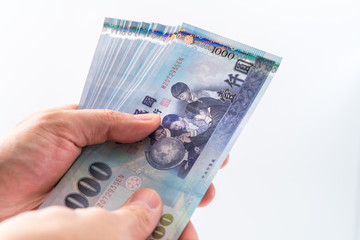 A hand holding a 1000 New Taiwan Dollar bill.