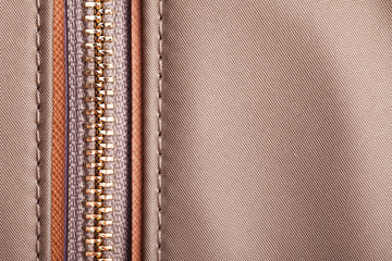 Brown handbag metal zipper closeup. Fashion fabric texture with thread sew.