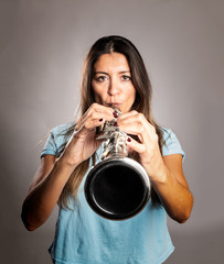 woman playing a clarinet on a gray background - obrazy, fototapety, plakaty