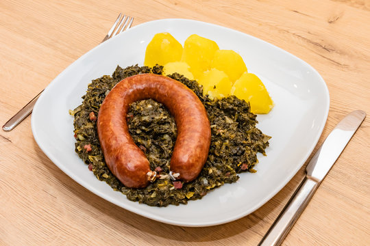 Norddeutsches Essen, Gr&uuml;nkohl mit Bregenwurst und Kartoffeln auf wei&szlig;en eckigen Teller