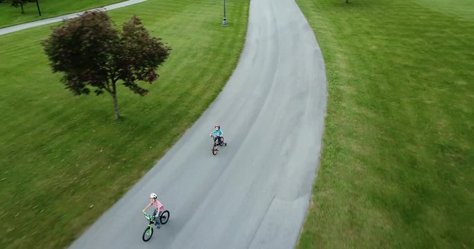 Young children riding bikes down driveway