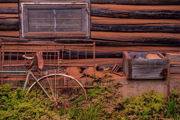 Picturesque view of the wooden house wall with parts of a bicycle and other metal objects coated with red pigment