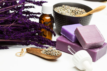 Jabones artesanales de lavanda junto a un ramillete de lavanda y esencia sobre fondo blanco aislado. Vista de frente