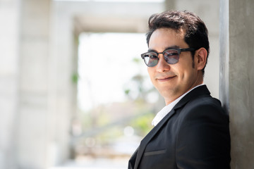 Obraz premium Happy Asian businessman standing in city with building background.