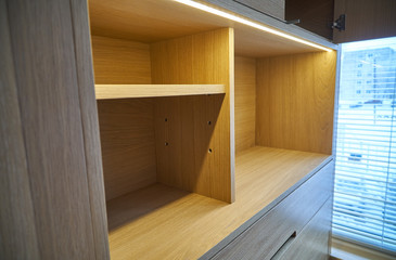 Wooden cupboard with drawers, empty shelves and LED lights. Modern furniture