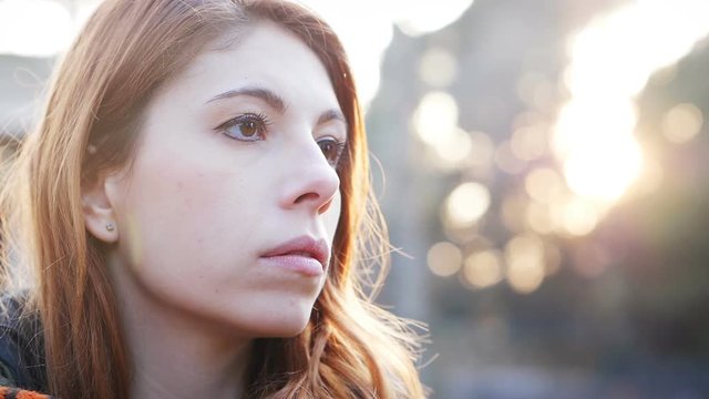 thoughtful sad red haired young woman in the park.Worries,sadness
