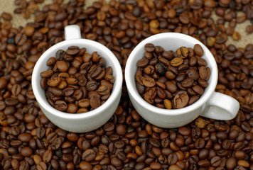 Cup of coffee full of coffee beans. Сoffee cup and coffee beans. Cup full of coffee beans on the cloth sack