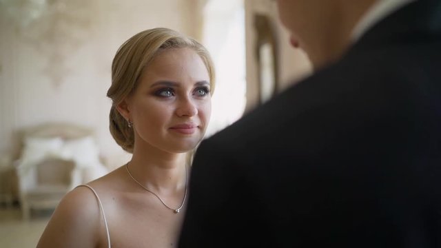 Look over groom's shoulder at happy crying bride. The bride sees the groom for the first time on their wedding day. The bride looks at the groom and cries.