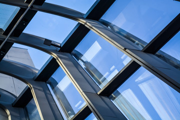 Modern buildings of unusual forms from glass and metal. Geometry of lines and curves. The inclined facade. Blue sky.