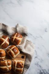 Traditional hot cross buns with raisins on a wooden board