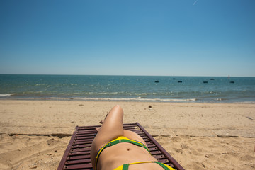 Young Woman Lying On Sunbed By The Sea And Tanning. Female Legs On Chaise-Longue