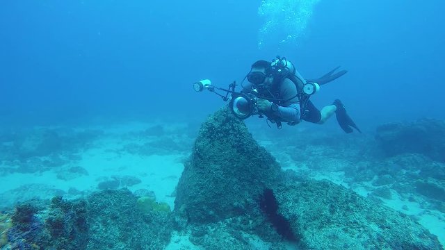 A slow-motion video of a underwater cameraman taking photos in the ocean of marine life with underwater equipment and lights