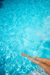 Female legs in the pool water. Up view