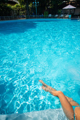 Female legs in the pool water. Up view