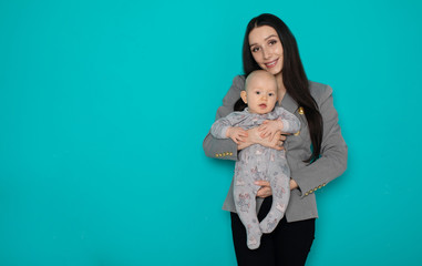 Young mother holding her newborn child. Woman and new born boy relax on color background. Mother breast feeding baby. Family at home. Young mother playing with her newborn son