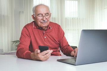 Retired man using computer technologies at home.