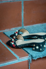 A pair of women's shoes with beads left on a step in front of a Buddhist temple in Hanoi, Vietnam