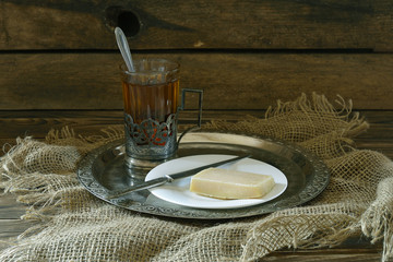 A glass of tea with a piece of cheese on a plate.