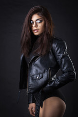 Brunette girl in a black leather jacket . Beautiful model on a dark background. Studio photosession
