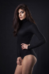 Brunette girl in a black leather jacket . Beautiful model on a dark background. Studio photosession