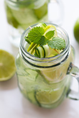 a glass of water, mint, lime and cucumber.