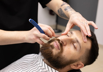Obraz na płótnie Canvas Client during beard shaving in barber shop 