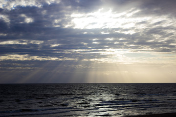 Sun trough cloudy sky in sea beach