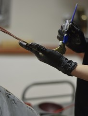 Hairdresser applying color female customer at salon, doing hair dye