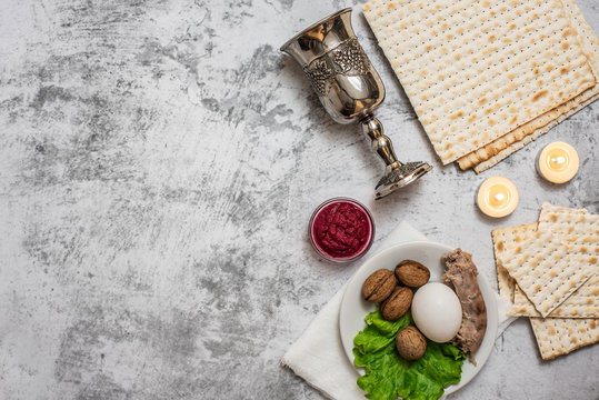 Jewish holiday Passover background with wine, matza and seder plate on grey. Top view. With copy space