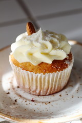 Homemade bakery style vanilla delicious sponge cake with white butter cream cream frosting and almond on top on plate. Candy bar for celebrating partys and birthdays