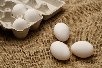 Eggs and egg carton on burlap sack cloth.