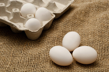 Eggs and egg carton on burlap sack cloth.