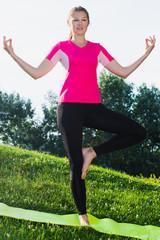 Sportswoman in pink T-shirt is staying and practising meditation