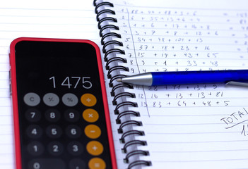 Phone calculator, notebook with calculations written by hand.